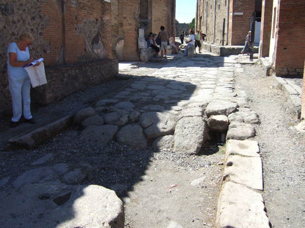 Via degli Augustali between VII.9 and VII.4. September 2005. Looking west towards junction with Via del Foro (on right) and Vicolo dei Soprastanti (ahead).  On the north side of the street appears to be a drain.