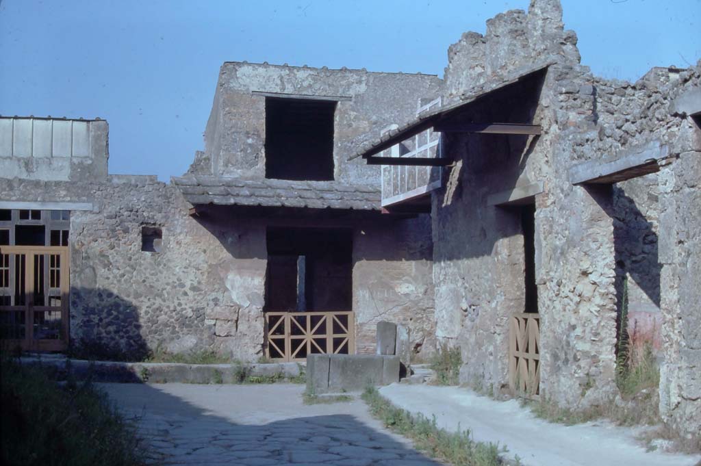 Vicolo del Menandro, Pompeii. August 1976. Looking east to end of the Vicolo with fountain at its junction with Vicolo di Paquius Proculus. 
On the right is I.10.1 and I.10.2. Photo courtesy of Rick Bauer, from Dr George Fay’s slides collection.
