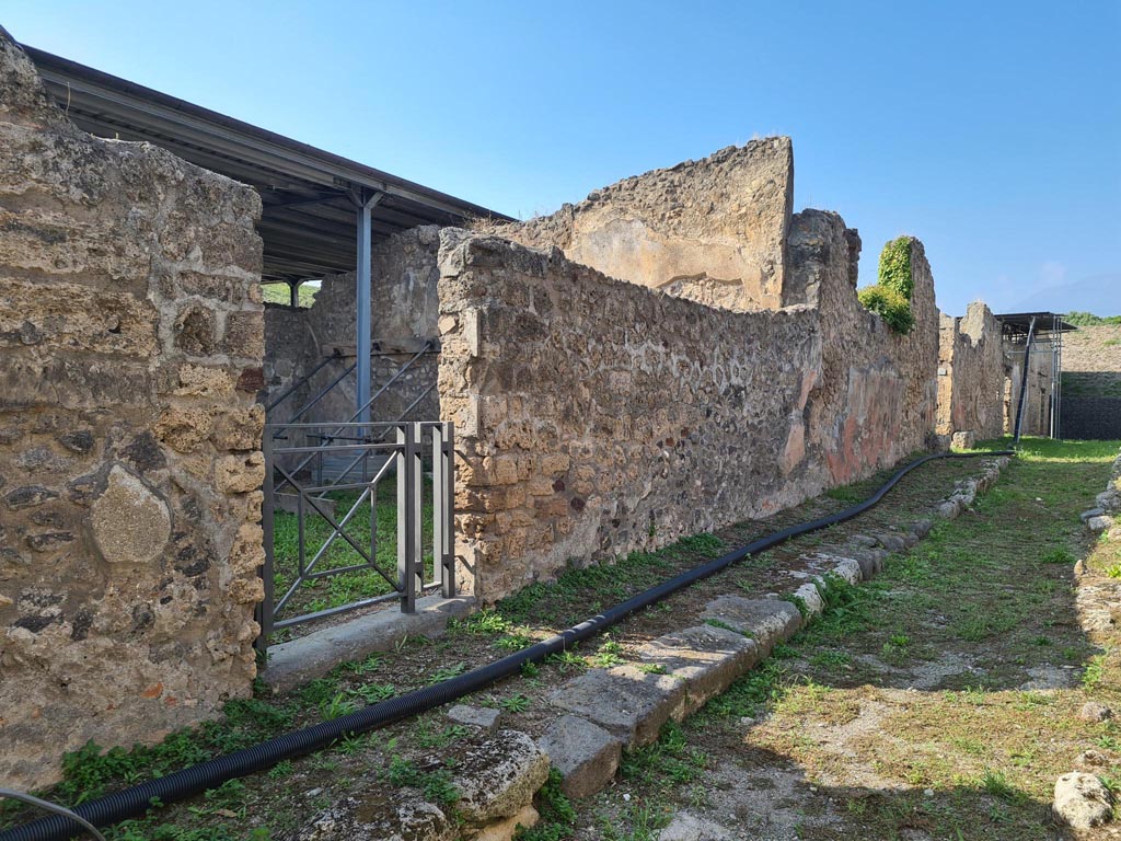 Vicolo di Lucrezio Frontone, Pompeii. October 2023. 
Looking north towards west side of roadway, and doorways at V.3.10, V.3.11 and V.3.12. Photo courtesy of Klaus Heese.