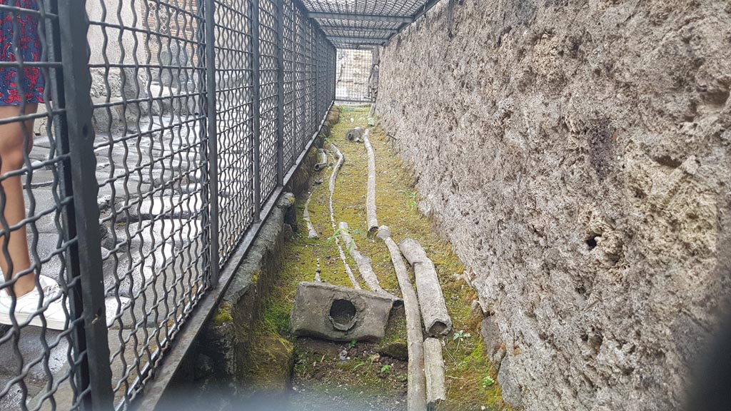 Vicolo di Mercurio. August 2023. 
Looking east along line of ancient water pipes on the edge of the road at the north end of VI.13. Photo courtesy of Maribel Velasco