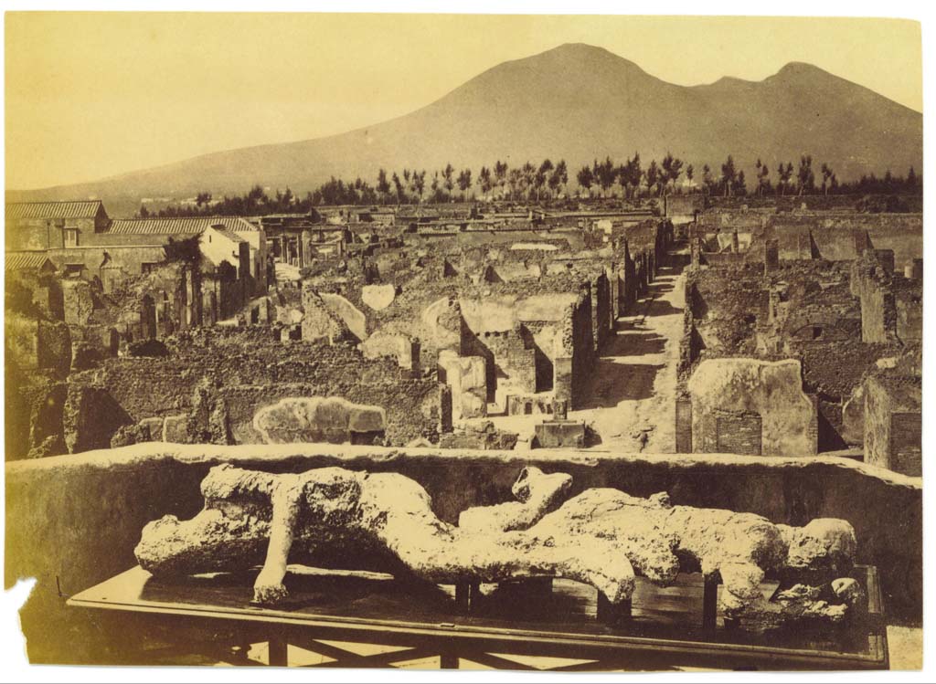 Vicolo di Modesto. Undated photograph but after 1863, with plaster-casts of victims numbered 2 and 3 (found in 1863). 
Photographed on an upper floor (possibly from VII.6.7), looking north towards Vicolo di Modesto and Vesuvius.
Centre-left can be seen the rebuilt School of Archaeology on Via Consolare. Photo courtesy of Eugene Dwyer.