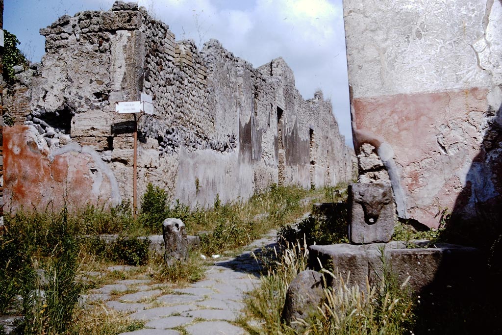 Vicolo di Tesmo, Pompeii. 1964. 
Looking north, with Vicolo di Balbo, on the left, and IX.7, on the right at rear of fountain. Photo by Stanley A. Jashemski. 
Source: The Wilhelmina and Stanley A. Jashemski archive in the University of Maryland Library, Special Collections (See collection page) and made available under the Creative Commons Attribution-Non-Commercial License v.4. See Licence and use details.
J64f1602