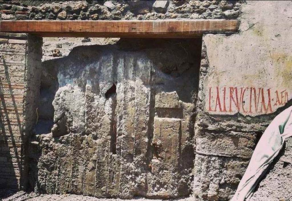 Vicolo c.d. dei Balconi, at north-west corner of junction with Vicolo delle Nozze Argento. June 2018. 
Last entrance to the east on the north side of Vicolo delle Nozze Argento with impression of doors in the ash and electoral inscription. 
Photograph courtesy of Parco Archeologico di Pompei.