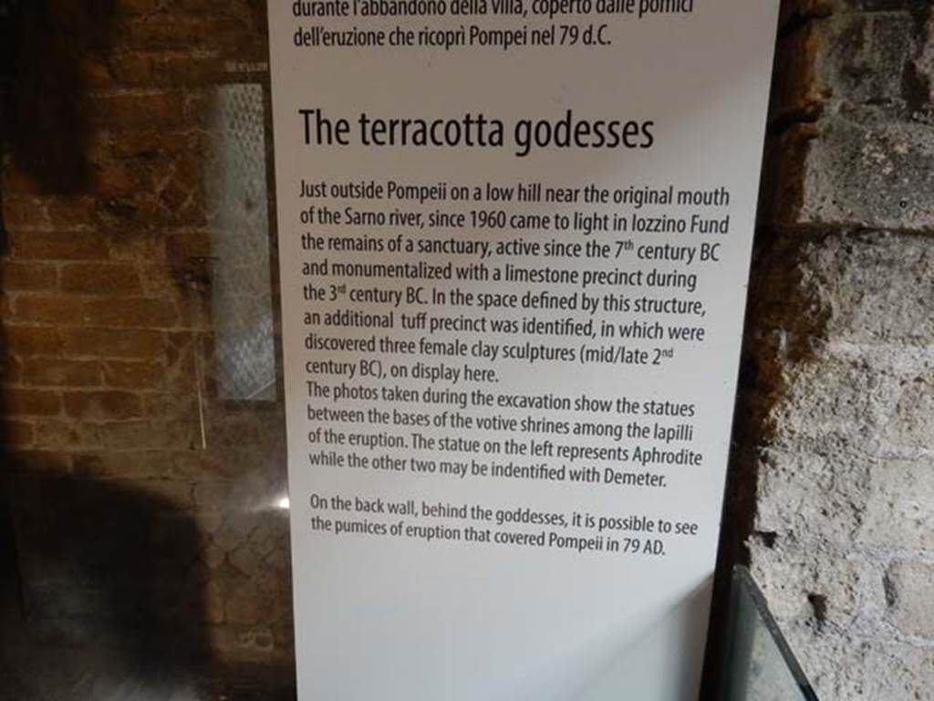 Santuario extraurbano del Fondo Iozzino. May 2018. Information card in the Antiquarium exhibition.
According to this, it was a place of worship as early as the 7th century BC and was monumentalized with a limestone precinct in the 3rd century BC. 
In the space defined by this structure, an additional tufa precinct was identified, in which were discovered three female clay sculptures dating to the mid to late 2nd century BC.
Photo courtesy of Buzz Ferebee.