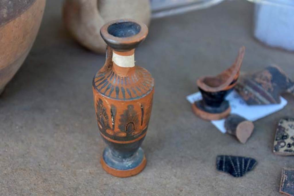 Santuario extraurbano del Fondo Iozzino. 2014 excavations. Perfume pot imported from Greece. A lekythos of attic production. A fragment of a black ceramic jug. To the right - fragments of a black ceramic jug.
Vaso di profumo importati dalla Grecia. Una lekythos di produzione attica. A destra frammenti di una brocca in ceramica nera.
Photograph © Parco Archeologico di Pompei.
Una brocca decorata con manico singolo e frammenti di una brocca in ceramica nera.
Photograph © Parco Archeologico di Pompei.