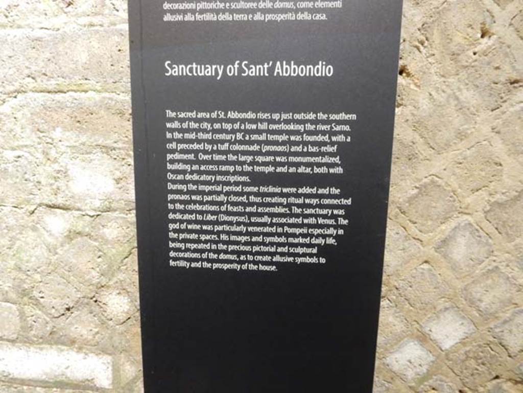 Tempio dionisiaco in località Sant’Abbondio di Pompei. May 2018. Antiquarium exhibition description of the temple.
According to the Parco Archeologico di Pompei, it is located just outside the city walls on top of a low hill overlooking the river Sarno.
A small temple was founded in the 3rd century BC with a cella preceded by a tufa colonnade (pronaos) and the low relied pediment. 
Over time the large square was monumentalised, building an access ramp to the temple and an altar, both with Oscan dedicatory inscriptions.
Some triclinia were added in the Imperial period and the pronaos partly closed creating ritual ways connected to the celebration of feasts and assemblies.
The sanctuary was dedicated to Liber (Dionysus), usually associated with Venus.
The god of wine was particularly venerated in Pompeii especially in the private spaces.
His images and symbols marked daily life, being repeated in the precious pictorial and sculptural decorations of the domus, so as to create allusive symbols to fertility and the prosperity of the house.
Photo courtesy of Buzz Ferebee.