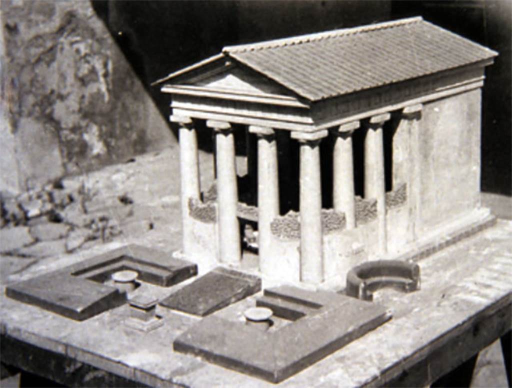 Tempio dionisiaco in località Sant’Abbondio di Pompei. Old undated photograph of reconstruction model of temple. 
The walls and columns were covered in heavy coats of stucco.
The pronaos was enclosed by screen with attached benches.
It was damaged in the earthquake of 62AD and repaired by the time of the AD79 eruption.
According to Cooley, this is an indication of how deeply culture and society in Pompeii were influenced by Hellenistic traditions during the second century BC
Pompeii had continued to renovate the temple after the Rome Senate decree of 186BC, which banned the worship of Dionysus. 
There is no evidence that the cult at Pompeii was interrupted.
The temple was still in use in 79AD.
See Cooley, A. and M.G.L., 2004. Pompeii: A Sourcebook. London: Routledge, p. 11.
See Cooley, A. and M.G.L., 2014. Pompeii and Herculaneum: A Sourcebook. London: Routledge, p. 15.