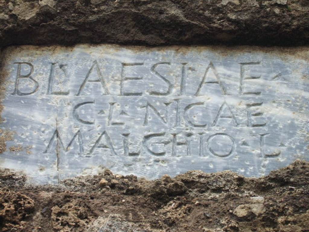 FPNH Pompeii. December 2005. Light blue marble plaque in centre of south side, with inscription.
According to D’Ambrosio and De Caro, this read
BLAESIAE C. L. NICAE MALCHIO L.
They expand this to
Blaesiae
C(ai) l(ibertae, Nicae 
Malchio l(ibertus)
See D’Ambrosio A. and De Caro S., 1988. Römische Gräberstraßen. München: C.H.Beck. p. 212.