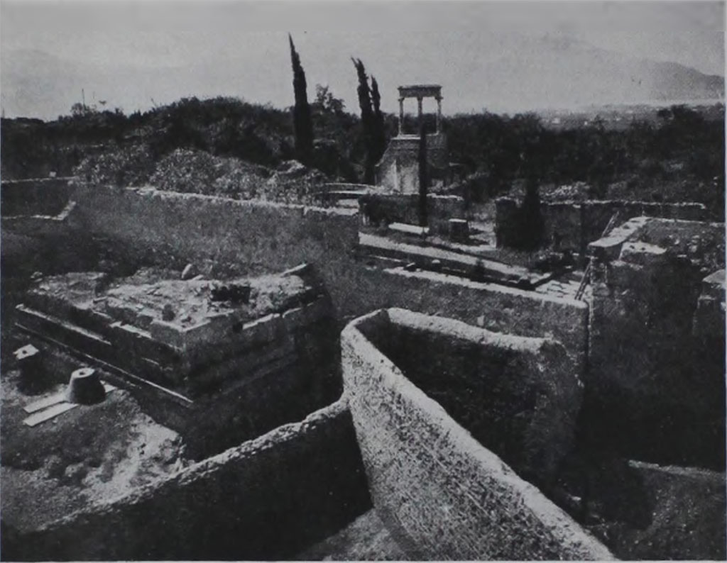 HGE04 Pompeii. 1933-5. View of rear of tomb during excavations showing also the cone found by Maiuri.
According to Kockel in 1933/35, A. Maiuri excavated the entire area between the city wall and the Villa delle Colonne a mosaico, completely exposing North 4 as well. 
To the north of the base he found a cone and a Corinthian capital to match.
See Kockel V., 1983. Die Grabbauten vor dem Herkulaner Tor in Pompeji. Mainz: von Zabern, p. 122. 
See Notizie degli Scavi di Antichità, 1943, p. 301, fig. 17.
