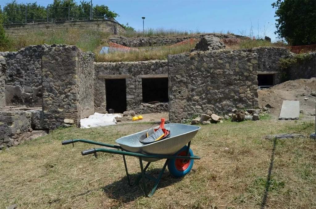 HGE20 Pompeii. June 2016. The shop where the five fugitives had taken refuge.
Here the archaeologists, while emptying the rooms of a workshop already explored in the nineteenth century by Giuseppe Fiorelli, came across a layer untouched by the nineteenth-century excavators and found the skeletons of five fugitives, who had found refuge in the workshop while trying to escape the fury of the eruption of Vesuvius in 79 AD: Alongside the bones, three gold coins, a necklace pendant and some tableware were found, mixed together after the looting by clandestine diggers who ventured into the workshop after the eruption of 79 AD. They had ventured into the city in search of treasures buried under the ashes. The area was damaged by bombing in 1943.
La bottega dove si erano rifugiati i cinque fuggiaschi.
Qui gli archeologi, mentre svuotavano gli ambienti di una bottega già esplorata nell'Ottocento da Giuseppe Fiorelli, si sono imbattuti uno strato non intaccata dagli scavatori ottocenteschi e hanno rinvenuto gli scheletri di 5 fuggiaschi, che avevano trovato rifugio nella bottega mentre cercavano si sfuggire alla furia dell'eruzione del Vesuvio del 79 dopo Cristo: accanto alle ossa sono state ritrovate tre monete d’oro, un pendente di collana e alcuni vasi da mensa, mescolati alla rinfusa dopo i saccheggi degli scavatori clandestini che dopo l’eruzione del 79 d.C. si avventurarono nella città alla ricerca di tesori sepolti sotto la cenere. La zona fu danneggiata dal bombardamento del 1943. 
Photograph © Parco Archeologico di Pompei.