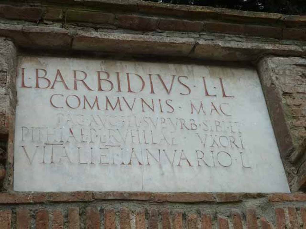 Pompeii Porta Nocera.  May 2010. Tomb 15ES. Marble plaque with Latin inscription:
L BARBIDIVS L(uci) L(ibertus)
COMMVNIS MAG(ister) 
PAG(i) AVG(usti)  FEL(icis) SVBVRB(ani) SIBI ET
PITHIAE P(ubli) L(ibertae) RVFILLAE VXORI
VITALI ET IANVARIO L(iberis).
Lucius Barbidius Communis was a freedman of Lucius Barbidius and a magistrate/priest of the Pagus Augustus Felix Suburbanus.
He constructed the tomb for himself, his wife Pithia Rufilla freedwoman of Publius Pithius, and their two sons Vitalis and Ianuarius.