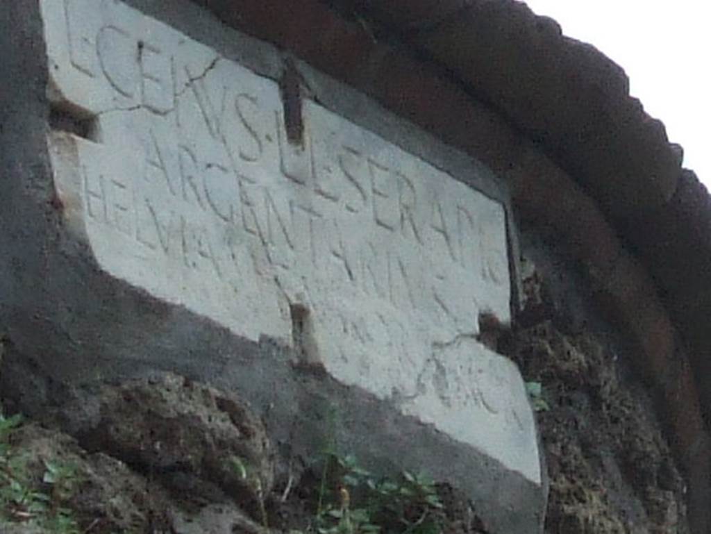 Pompeii Porta Nocera Tomb 3OS. Marble plaque with latin inscription:
L(ucius)  CEIVS  L(ucii)  L(ibertus)  SERAPIO
ARGENTARIVS
HELVIA  M(arci)  F(ilia)  VXOR  SACR(averunt).