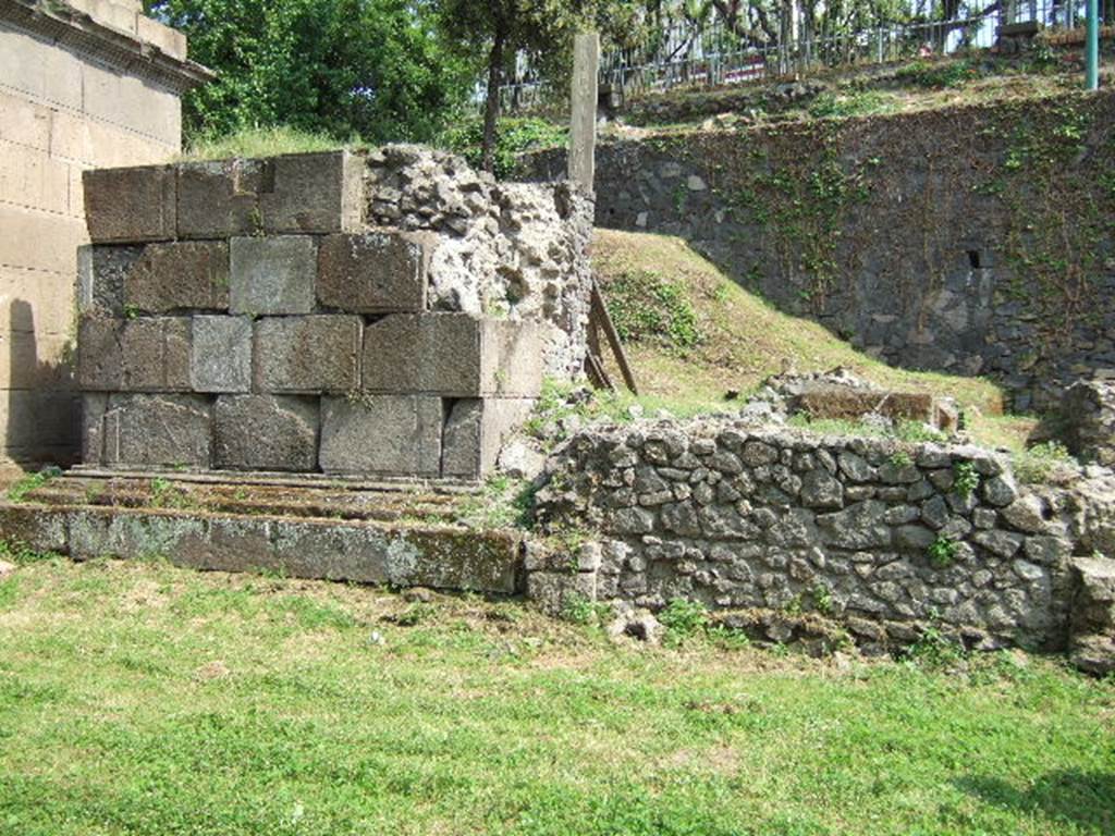 Pompeii Porta Nocera Tombs 19aOS and 19bOS behind 19OS. Looking across 21OS to rear of tomb 19OS.
Tomb 19aOS was an enclosure or recinto at the shoulder of tomb 19OS. It is now completely buried.
A marble columella was found with the inscription 
HELLE  PVEL
LA  VIXIT  AN
NIS  IV.
This reads as 
Helle Puella vixit annis IV
The tomb name is unknown, and according to De Caro, it is unlikely to be that of the four year old slave Helle Puella.
Tomb 19bOS was further to the south behind tomb 19aOS close to the escarpment forming the boundary of the tombs. 
This also is not visible today.
See D’Ambrosio, A. and De Caro, S., 1983. Un Impegno per Pompei: Fotopiano e documentazione della Necropoli di Porta Nocera. Milano: Touring Club Italiano. (19aOS, 19bOS).