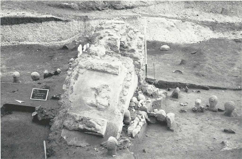 Pompeii Porta Sarno Necropolis. 1998. Necropoli romana presso via Nolana. Il monumento funerario in crollo. Nell'area sepolcrale spicca un grande podio, in opera incerta intonacata su tutti i lati, sulla cui faccia superiore, delimitata da sponde modanate, resta traccia della parte inferiore di una statua di grandi dimensioni. In particolare, si riconosce la parte anteriore dei calzari e, sul lato posteriore, l'appoggio del bordo di una lunga tunica.
Roman necropolis near via Nolana. Collapsed funerary monument. In the burial area stands a large podium, in opus incerta work plastered on all sides, on whose upper face, bordered by moulded sides, remains traces of the lower part of a large statue. In particular, the front of the shoes and the back of the edge of a long tunic can be recognized.
See D'Ambrosio A. Scavi e Scoperte nel suburbio di Pompei. Rivista di studi Pompeiani IX, 1998, p. 198, fig. 2.