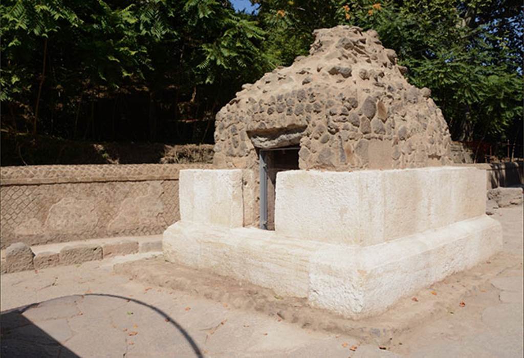 SG4 Pompeii. 2018. Side facing south away from the Stabian Gate.
The tomb, which is rectangular in shape, is formed of two rows of white limestone parallelepiped blocks; the tomb was probably crowned with an altar shaped element. 
On three sides the plastered interior has rectangular niches, while the fourth includes the access to the chamber. At the time of the restoration work inside the burial chamber - which was in a poor state of conservation - it was revealed that only four of the nine clay urns fixed into the two raised areas along the sides of the chamber had previously been emptied, probably during the nineteenth century explorations, which brought about the destruction of the limestone coating of the upper part of the tomb and the removal of the glass urns in the niches. 
Of the 5 urns which had not been previously emptied, two revealed the ashes of the deceased, while another two contained the remains of the ustrinum (funeral pyre), such as glass unguentaria deformed by the heat, and in one case a coin placed as a Charon’s obol (fee/bribe for ferrying). Some urns retain their lids in the closed position but inverted. 
A clay conduit was discovered on the cocciopesto floor, for the libations in honour of the deceased which took place during the various festivities; the conduit was closed by a marble element.
See http://pompeiisites.org/en/comunicati/the-tombs-of-the-necropolis-of-porta-stabia/