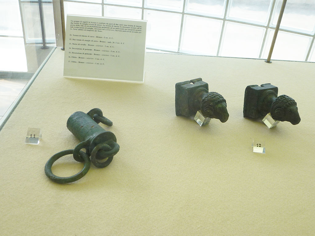 Villa della Pisanella, Boscoreale. September 2011. Bronze cart shaft parts, one round with rings attached and two square ends decorated with a rams head.
Now in Boscoreale Antiquarium. Photo courtesy of Michael Binns.