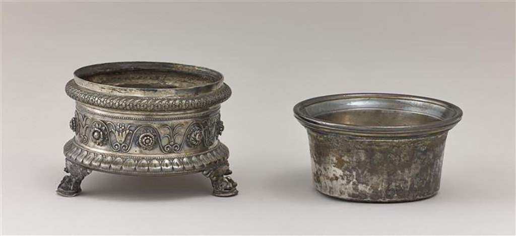 Villa della Pisanella, Boscoreale. Boscoreale Silver. Miniature tripod with zoomorphic foot supporting a salt cellar. 
Guilloche decoration, tongues and friezes of palmettes and flowers. Owners name engraved in Latin: Pamphilus, imperial freedman.
Trépied miniature avec pied zoomorphe supportant une salière. Salière : décor de guillochis, languettes et frise de palmettes et de fleurs. 
Nom propre gravé en latin : Pamphilus, affranchi impérial.
Now in the Louvre, inventory number BJ1999.
Photo © RMN-Grand Palais (musée du Louvre) / Stéphane Maréchalle.