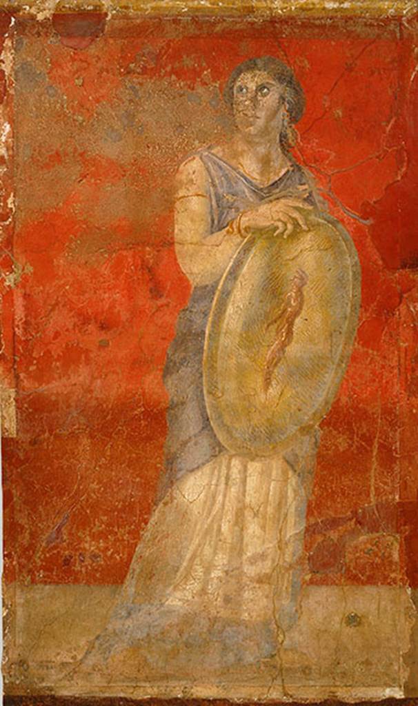 Villa of P Fannius Synistor at Boscoreale. Room H south end of east wall.
Standing woman clad in a white chiton and blue cloak, and holding a gold shield in her right hand. H
She is turning her head upwards to gaze towards the wall with Venus. 
The front of the shield shows the image of a standing nude male figure who is adorned with a white headband, the same as those worn by Hellenistic dynasts. 
This small male figure has been described as a reflected image on the shield, a popular motif in Hellenistic art. 
However, since there is no image in the fresco cycle that corresponds to a reflection, the figure should be understood as an apparition, which, in antiquity, was viewed as prophetic. 
The small apparition with a portrait like head in this particular fresco may refer to a Hellenistic royal heir, and the woman bearing the shield may represent a priestess or prophetess.
Photo © The Metropolitan Museum of Art, Rogers Fund 1903. Inventory number 03.14.7.
See www.metmuseum.org
See Barnabei F., 1901. La villa pompeiana di P. Fannio Sinistore. Roma: Accademia dei Lincei. p.57, Fig. 12.