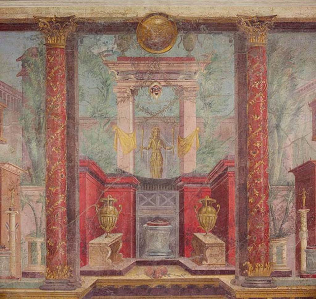 Villa of P Fannius Synistor at Boscoreale. Cubiculum M, second panel from south end of west wall. According to Barnabei, this wall painting depicts a golden statue of Diana Hecate bearing torches. She was the goddess who scattered her benefits on the end of life on those who protected it. She welcomed them, in peace underground, among the ranks of the blessed in the happiness of Elysium. In the painting she has a gold crown with serpents’ heads and necks on the top. Her chest was crossed by a white band to which was attached the quiver, visible behind the right shoulder. She is within a sacred portal wrapped in yellow ribbons. From the portal hangs a bearded mask of an old silenus above which a lintel is supported on the wings of two swans. On top of the lintel are two silver urns and between them is a round gold shield. At the base is a small red walled area with an altar with offering on top and two vases on benches. Either side are red columns painted with flowers and climbers. See Barnabei F., 1901. La villa pompeiana di P. Fannio Sinistore. Roma: Accademia dei Lincei. p.74, Fig. 17.
