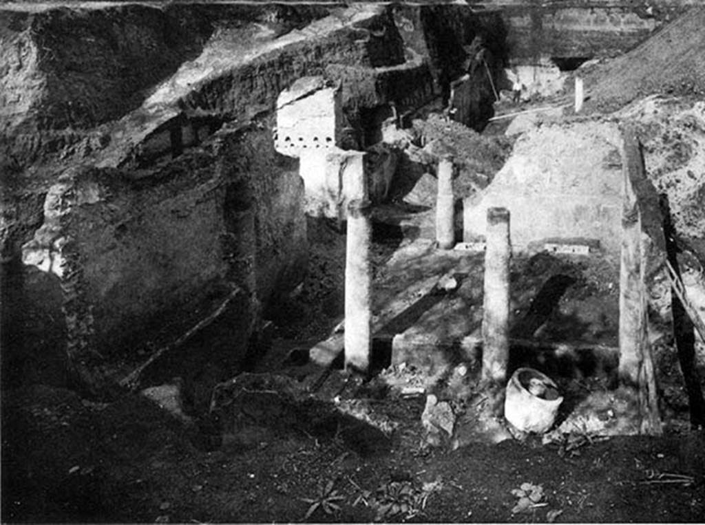 Villa of P. Fannius Synistor at Boscoreale. Room 24, work area during reburial in Mid September 1900.
According to Barnabei, the whole building was the owner’s house, except a portion (room 24) to the left of the entrance, which was used for the business.
A press for the grapes was discovered here, as well as a pitcher for the must.
An olive press (trapetum), a wine press (torcularium) and farming tools were found here.
There were also some bronze vessels, one of which had a handle of a figurine representing Bacchus, clad in silver leaf.  
See Barnabei F., 1901. La villa pompeiana di P. Fannio Sinistore. Roma: Accademia dei Lincei. Tav. XI.