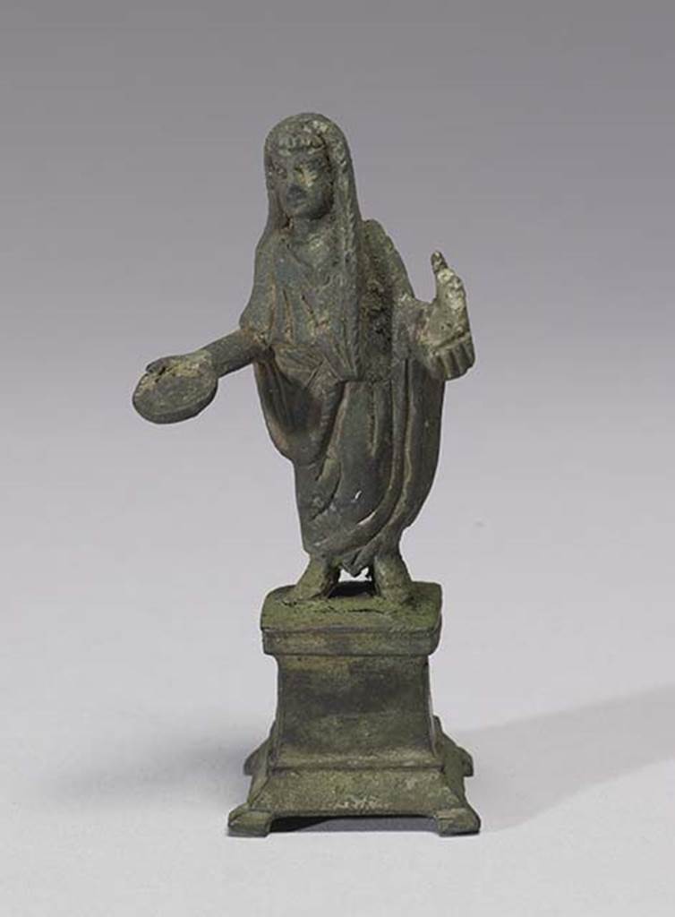 Boscoreale, Villa rustica in fondo D’Acunzo. Room 12, lararium. 
Bronze statuette of sacrificing priest, 0.08m high, front view.
According to Della Corte,  this represented a Genius familiaris, wearing the toga with a fold drawn up over his head.
He holds a patera in his right, and an acerra (small box) with incense in his left. 
See Notizie degli Scavi di Antichità, 1921, p. 440.
Photo courtesy of The Walters Art Museum, Baltimore. Inventory number 54.752.
http://thewalters.org/
Creative Commons Attribution-ShareAlike 3.0 Unported Licence