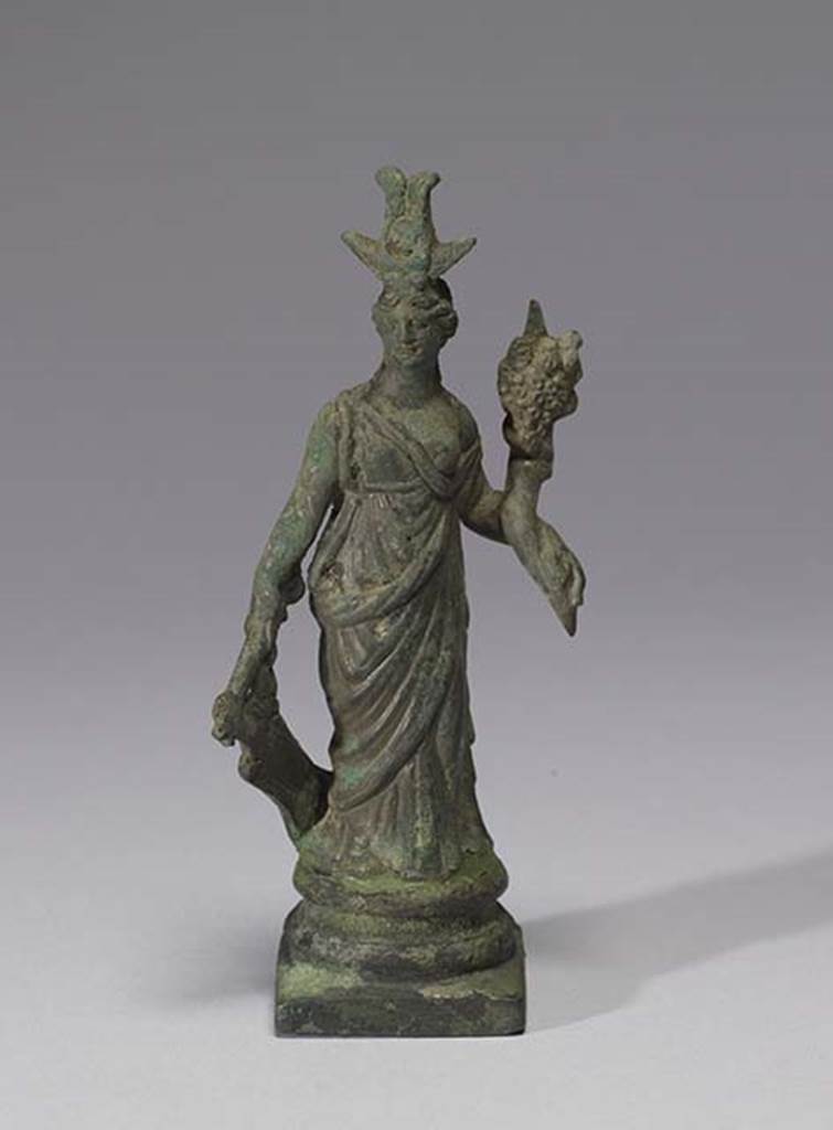 Boscoreale, Villa rustica in fondo D’Acunzo.Room 12, lararium. 
Larger bronze statuette of Isis-Fortuna, 0.12m high including the base, front view.
She is fully clothed and has a crescent moon and a disk surmounted by two plumes upon her forehead.
In her right hand she holds a rudder, in her left hand a cornucopia.
Photo courtesy of The Walters Art Museum, Baltimore. Inventory number 54.751.
http://thewalters.org/
Creative Commons Attribution-ShareAlike 3.0 Unported Licence