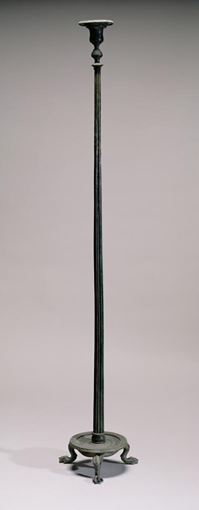 Villa in Boscoreale. Bronze candelabrum with silver inlays.
Digital image courtesy of the Getty's Open Content Program. Now in the Getty Museum, inventory number 72.AC.131.
One of a pair of identical bronze candelabra (lampstands) that once belonged to the household furnishings of a Roman villa (see also 72.AC.132). Architectural in inspiration, these candelabra take the form of a tall fluted column rising from a base with three lion’s paws. At the top, a vase-shaped element supports a circular disk designed to hold an oil lamp. The decoration around the disk includes intricate patterns of tongues and florals. Both candelabra are formed from several separately made and assembled components: the tripod base, a fluted shaft, the vase-shaped decorative element, and finally the circular plate on which the lamp sat. The individual parts of the stand are decorated with a variety of relief mouldings and floral designs. The kidney-shaped pattern midway down the krater-shaped element of the candelabrum even has silver inlay. Designed to support an oil-burning lamp, many stands of this type have been discovered in houses at Pompeii, Herculaneum, and Boscoreale, which were destroyed by the eruption of Mount Vesuvius in A.D. 79. The height of this candelabrum indicates that it was meant to stand on the floor, but shorter, tabletop versions are also known. Originally, ornate metal lamps and lampstands were used to illuminate temples, sanctuaries, and other public spaces. However, by the first century A.D. they had become typical household items in wealthy private homes. Elaborate bronze candelabra, such as this one, were transformed from utilitarian objects into extravagant showpieces.