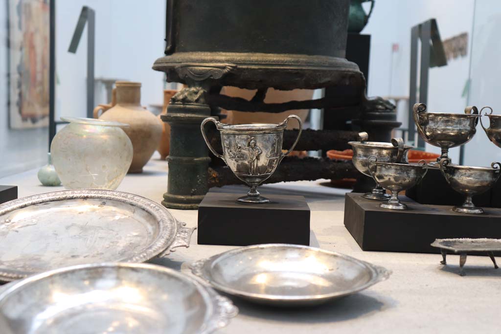Complesso dei triclini in località Moregine a Pompei. February 2021. Silver found in the Complex of the Moregine Triclinia on display in Pompeii Antiquarium.
Silver table set consisting of 20 pieces: a circular serving tray, four bowls/plates, ten cups – two embossed – four stands and a teaspoon.
The inscription, Erasti sum, engraved on the back of the silverware indicates that the owner’s name was Erastus.
Photo courtesy of Fabien Bièvre-Perrin (CC BY-NC-SA).
