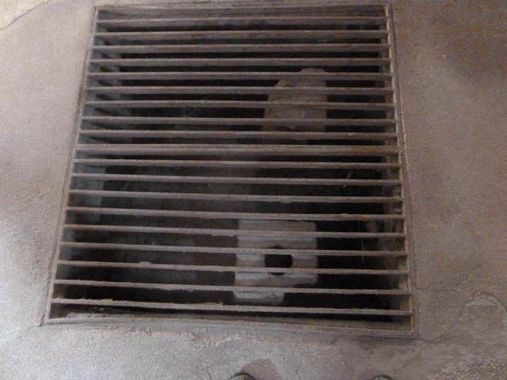 Oplontis, September 2015. Room 18, suspensurae beneath floor.
Secondo a Carlo Malandrino –
“Era l’ambiente a temperatura tiepida perche era riscaldato solo dai gas caldi che fluivano atttraverso il pavimento sospeso. Sono visibili le bocchette dell’impianto.”
See Malandrino, Carlo, 1978. “Oplontis” , (p.72).
(translation: It was a room with a warm temperature, because it was only heated by warm air that flowed through the suspended floor. The “suspensurae” under the floor, are visible through a metal grate, and are made up of brick pilasters. ) On p.72, this room according to Malandrino’s plan is described as room 17.