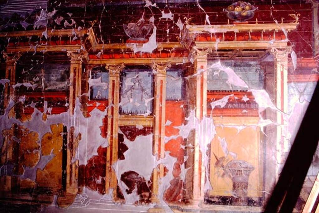 Oplontis, 1974. Room 23, at the top of the wall is a still-life of a glass bowl of pomegranates, and below it is a painted basket of fruit covered with a veil. 
Photo by Stanley A. Jashemski.   
Source: The Wilhelmina and Stanley A. Jashemski archive in the University of Maryland Library, Special Collections (See collection page) and made available under the Creative Commons Attribution-Non Commercial License v.4. See Licence and use details. J74f0649