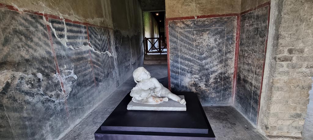 Oplontis Villa of Poppea, January 2023. 
Statuette of white marble young child with goose, on display in Corridor 63, looking west but may be from room 32. 
Photo courtesy of Miriam Colomer.
According to the PAP Oplontis Guidebook, it is believed that the small statue of a boy with a goose that was found in one of the porticoes overlooking the garden, used as a fountain, presumably would have been originally placed on the small fountain in the centre of this open space. 
Guide to the Oplontis Excavation. 2018. Parco Archeologico di Pompei, p. 40.