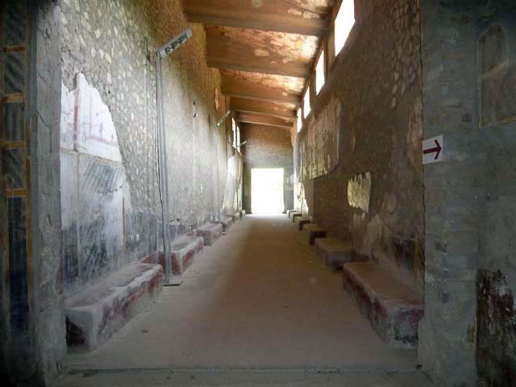 Oplontis, May 2011. Corridor 46, looking east towards doorway to west portico and pool area. The corridor contains 12 benches/supports which line the corridor on both sides. The lower walls are painted blue, with a “zebra striped pattern”, the upper walls would have been painted in white and red. Photo courtesy of Buzz Ferebee.
