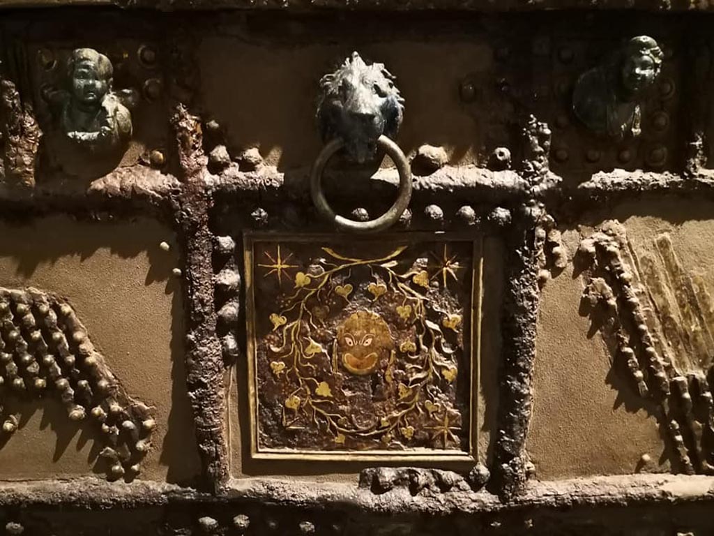 Oplontis, Villa of Lucius Crassius Tertius. December 2019. Strongbox decoration of inlaid silver and copper head of the satyr Silenus surrounded by twisting vines in centre. 
On display in exhibition “Pompei e Santorini” in Rome, 2019. Photo courtesy of Giuseppe Ciaramella.