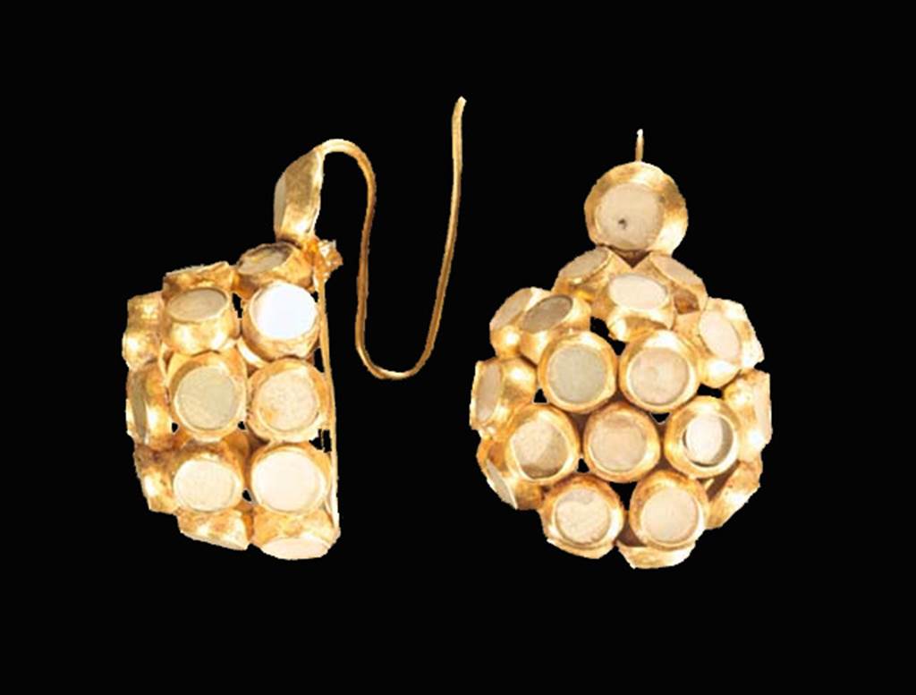 Oplontis, Villa of Lucius Crassius Tertius. Room 10. Pair of gold ear rings with quartz inserts. 
These were recovered in a leather bag containing amongst other things gold coins, a silver spoon, several glass bottles (unguentarium) and the remains of a gold hair net.
See D’Ambrosio A., 1987. Rivista di Studi Pompeiana I, p. 175-6, fig. 43, fig. 47.
According to D’Ambrosio, these were a rare variant of a basket ear ring with 26 small sheet gold bezels welded together to form a hemi-spherical shape into which quartzes have been inserted.
See D’Ambrosio, A., 2001. Women and Beauty in Pompeii. Roma: Bretschneider, p. 54, fig. 14.
SAP inventory number 73326.