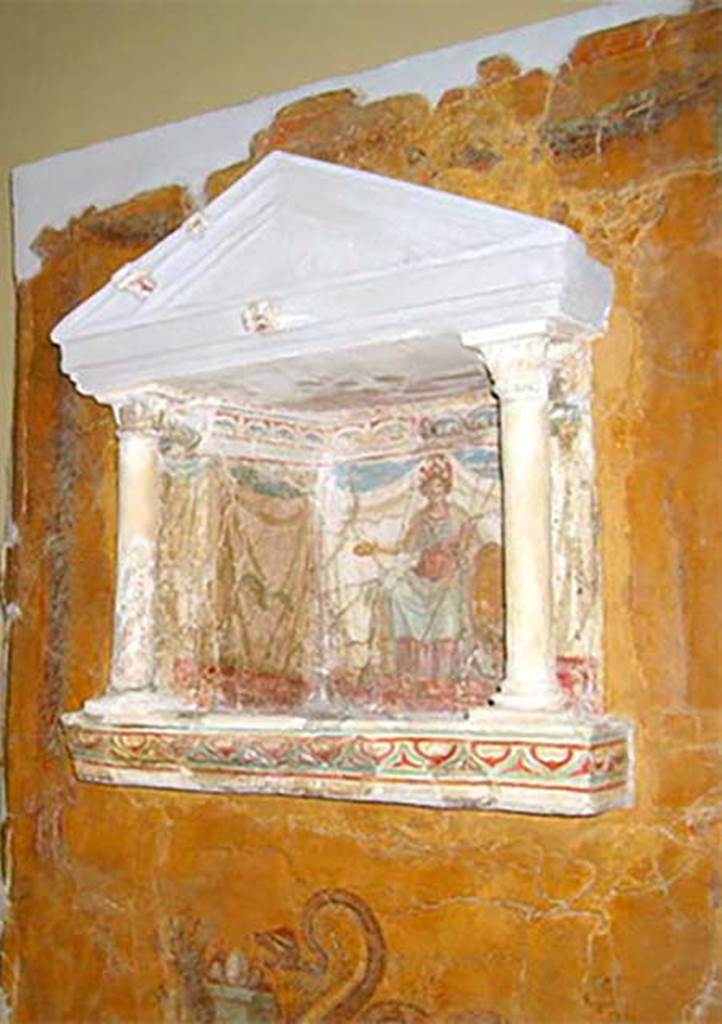 Gragnano, Villa rustica in Località Carmiano, Villa A. Lararium niche. 
From dividing pilaster between kitchen room 4 and room 2. 
Lararium in stucco found inserted in a yellow painted wall.
The lararium had a triangular pediment supported by two Corinthian columns.
The painting at the rear showed an enthroned Minerva with breastplate, helmet, shield, lance in the left hand and gilded/golden plate in the right.