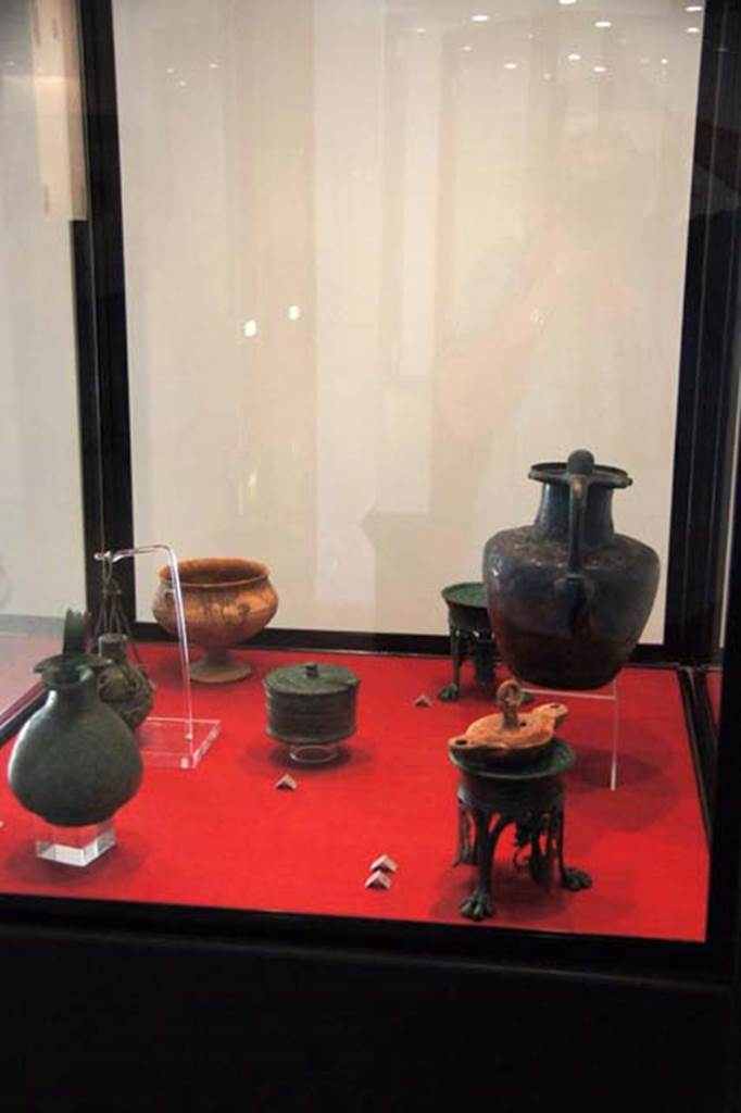 Gragnano, Villa rustica in Località Carmiano, Villa A. Items found in various rooms.
Stabiae Antiquarium, inventory numbers 
63539 bronze wine jug with trefoil mouth, found in room 6.
63437 bronze hanging perfume holder, found in room 1.
63464 terracotta cup on a tall trumpet foot, found in room 7.
63528 circular bronze pyx with hinged lid, found in room 9.
63278 63279 bronze lamp stands, found in room 2.
63543 terracotta hanging lamp with nozzles at each end, found in room 6.
63377 bronze jug with ribbon rim, found in room 4.
Photo courtesy of Margaret Hicks.
See Guzzo, P, Bonifacio, G, and Sodo, A.M., curated by (2007) Otium Ludens. Castellammare di Stabia: Nicola Longobardi, pp. 164-6.
See Bonifacio G., 2004. In Stabiano: Exploring the Ancient Seaside Villas of the Roman Elite. Castellamare: Nicola Longobardi, p. 137.