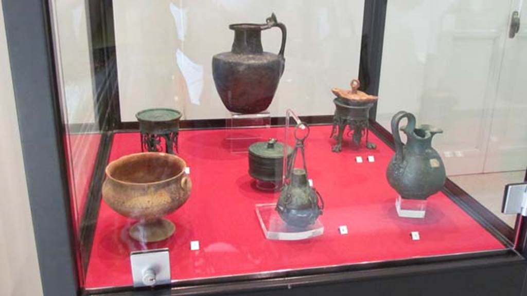 Gragnano, Villa rustica in Località Carmiano, Villa A. 
Stabiae Antiquarium, inventory numbers 
63464 Cup left found in room 7. 
63528 bronze perfume holder (centre) found in room 1. 
63437 pyx (behind) found in room 9. 
63377 jug (rear) found in room 4.
63278 (left rear) 63279 (right rear) lamp stands found in room 2.
63543 lamp found in room 6. 
63539 jug (front right) found in room 6.
Photo courtesy of Donna Dollings.
