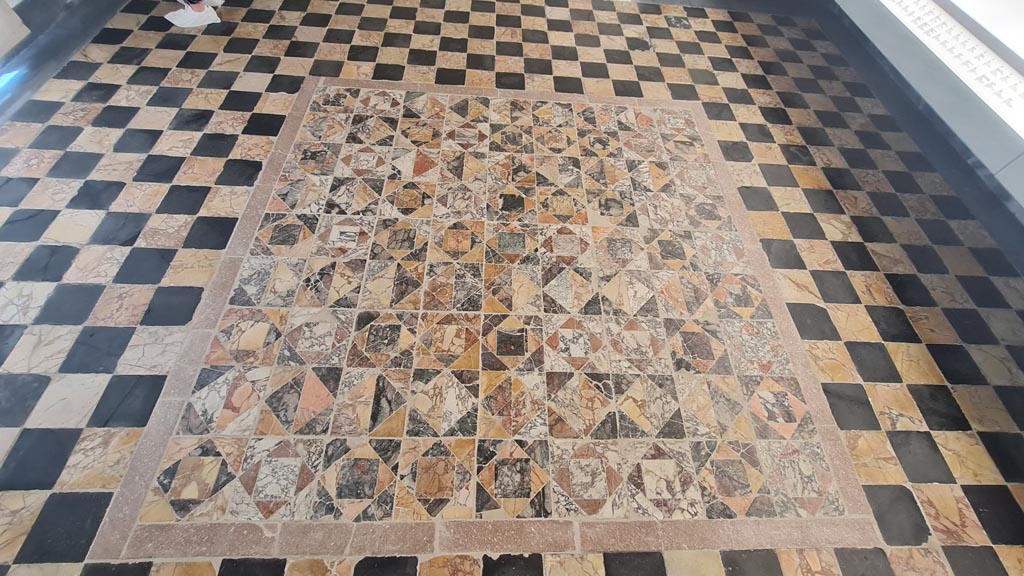 Opus Sectile floor on display in room CXLII on First floor in Naples Museum. June 2024. Photo courtesy of Giuseppe Ciaramella.
According to Ruggiero –
104 - “Il pavimento e scandita da un reticolo, formato da una fascia di marmo cipollino, nei cui scomparti sono racchiuse serie di quattro quadrelli. Questi sono formati da un quadrato sulla punta attorno al quale sono quattro triangoli che alternano i colori.”
(The floor is punctuated by a grid, formed by a band of cipollino marble, in whose compartments a series of four squares was enclosed. These are formed by a square, at the tip around which are four triangles of alternating colours.)
See Ruggiero, M. Degli scavi di Stabia dal 1749 al 1782, (p.119).
See Pisapia, M. S. 1989, in Mosaici antichi in Italia, Regione prima. Stabia, Roma, Room 104: p.54-55. (Room 104 is the same as our Room 13).