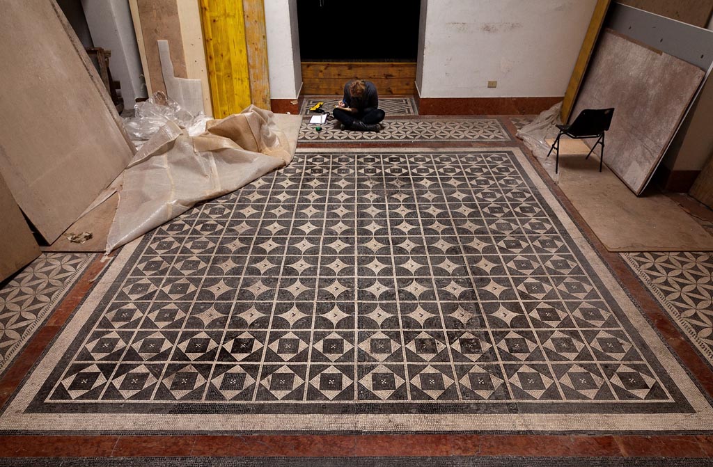 Naples Archaeological Museum, Room CXXIX. March 2013. Photo by Thomas Crognier for the ©Villa Diomedes Project, Image database.
Room CXXIX, however, has a mosaic carpet in the centre with rows of solid black circles, surrounded by a band of white rhombuses, inscribing squares alternating with black triangles.
Around the edge of the central mosaic are 3 (probably 4 but not all shown above) pieces of mosaic measuring 4.10m x 0.92.
This is possibly from the Second Complesso at Stabia. 
(Note: now Room CXXIX has been carpeted with a modern flooring, and these mosaic can no longer be seen there.)
(See Pisapia, no. 117 (p.580).