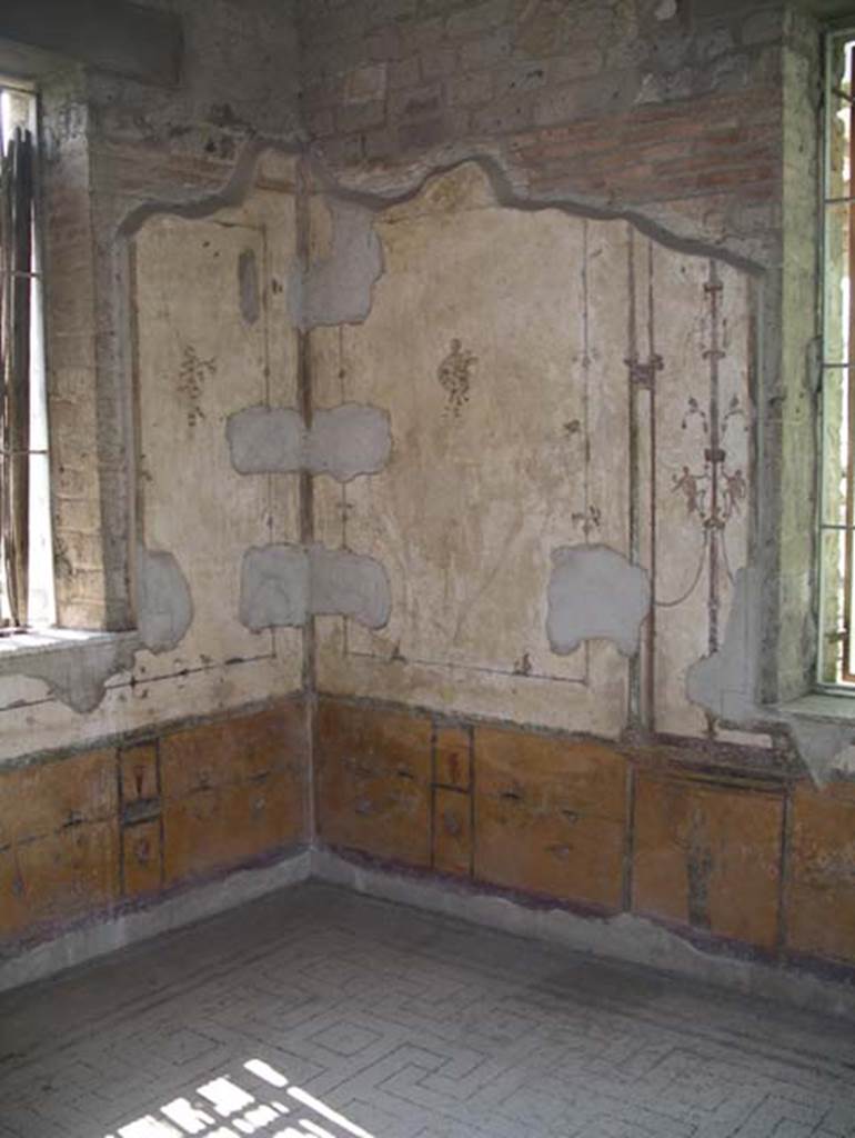 Villa Arianna, April 2005. Room 12, IV Style painted decoration in a corner of a room with two windows, a yellow zoccolo (dado) and walls with white background.
Photo courtesy of Michael Binns.