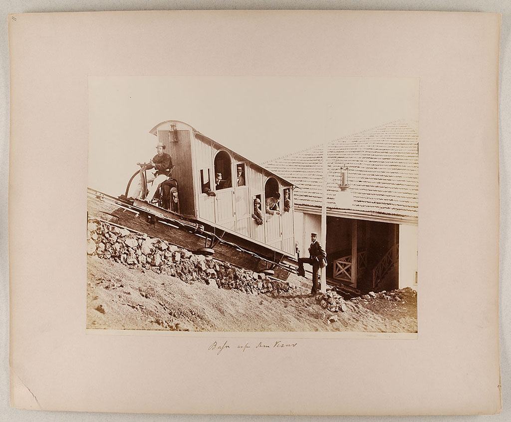 Vesuvius Funicular railway. An original 1880 car at the lower station, 1880-1889. 
Photo title at bottom is 8124 Vesuvio Stazione inferiore, G. Sommer Napoli. 
The handwritten note says “Bahn auf den Vesuv”.
Museum für Kunst und Gewerbe Hamburg, inventory number P1981.399 (Public Domain).
See https://sammlungonline.mkg-hamburg.de/de/object/8124-Vesuvio-Stazione-inferiore/P1981.399/mkg-e00135741