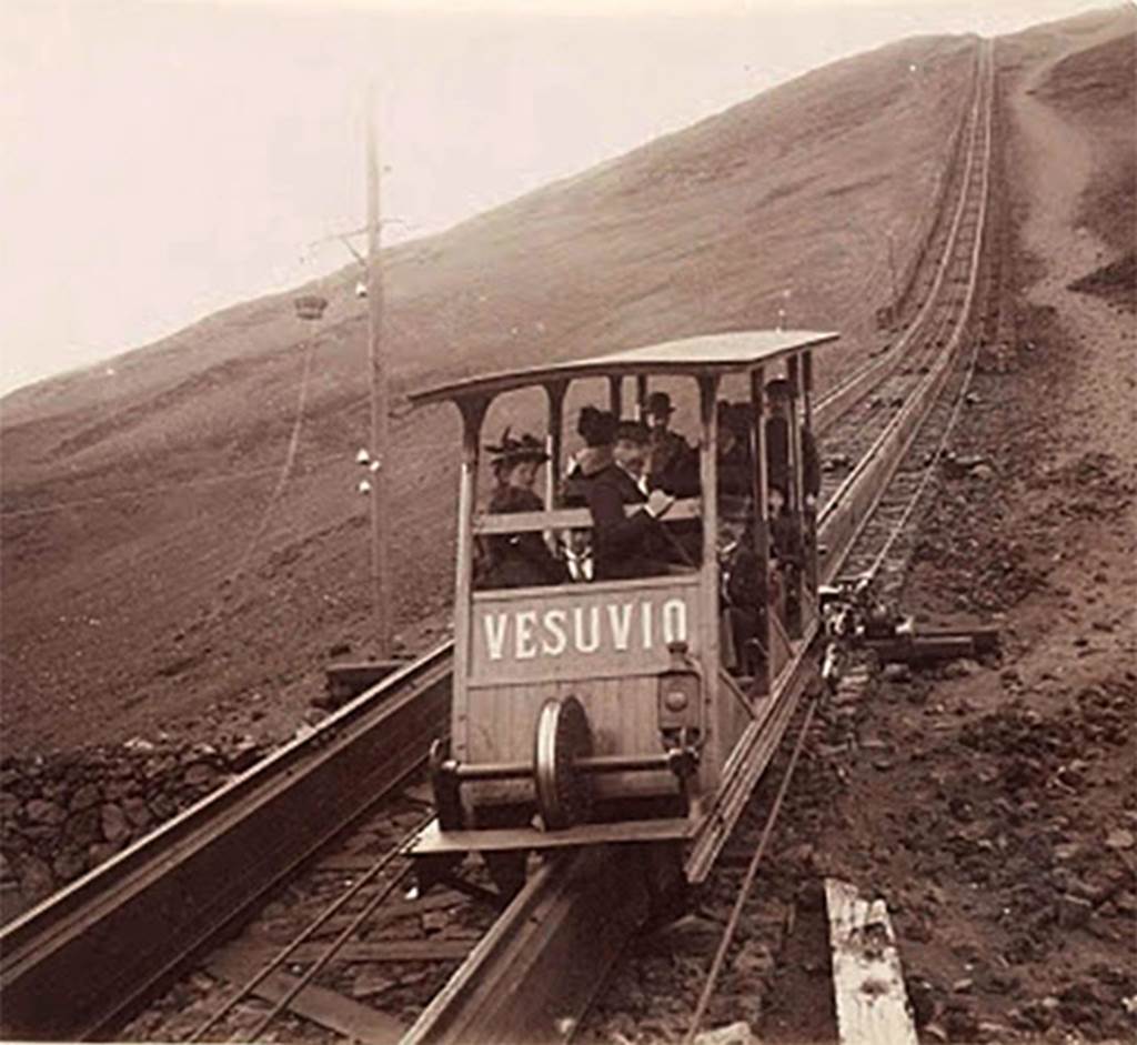 Vesuvius Funicular car Vesuvio. Undated black and white photo but must be between 1889 and 1904.
There was a longitudinal wooden sleeper on the top of which was carried a single rail. 
The cars had a double flanged wheel at each end which ran on this rail. 
In addition, there were two angled rails, one fixed to each side of the sleeper at its base. 
The cars had wheels mounted from their floors which engaged on these side rails and kept the cars upright. 
Each track had two continuous cables carried on pulleys which were fixed to each side of the car.