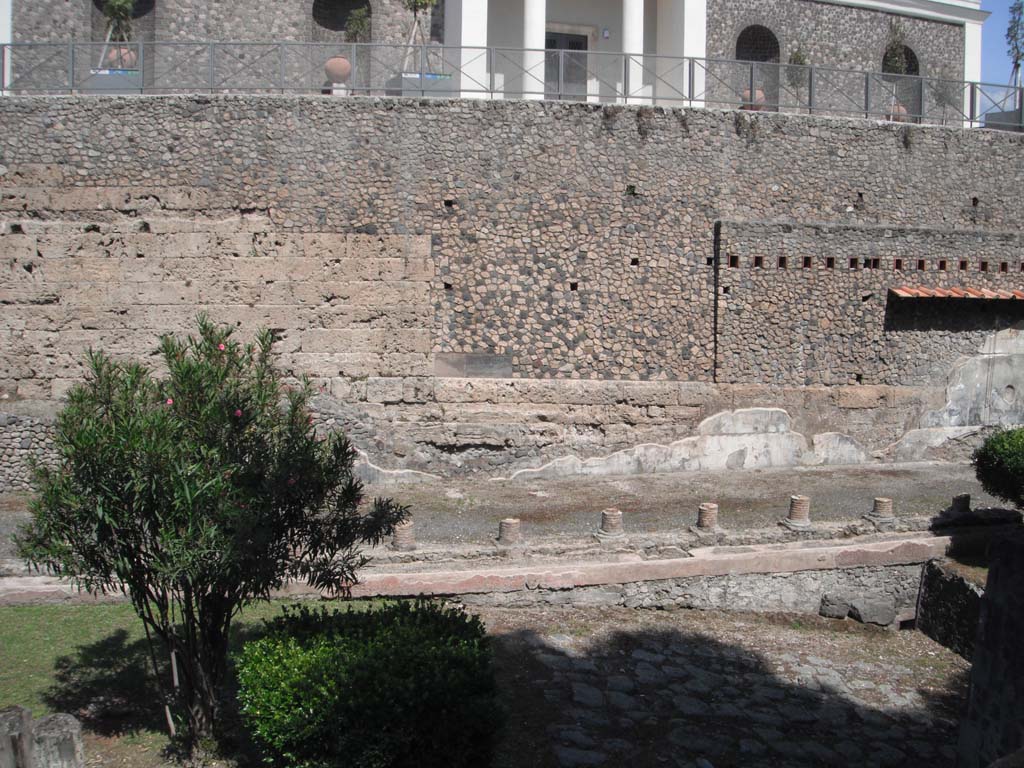 Walls on south side of Porta Marina, Pompeii. June 2012. 
Looking east towards Antiquarium, above, and Suburban Villa, below. Photo courtesy of Ivo van der Graaff.
According to Van der Graaf –
“South of the Porta Marina opus incertum superimposed on a few older travertine courses acts as a terrace for the Temple of Venus.
A lonely block of tuff suggests that the masonry replaced an earlier travertine/tuff curtain. The so-called Villa Imperiale (VIII.1.a) enveloped this section of the fortifications in the last first century BCE, covering them with Third Style frescoes and burying the external pomerial street.”
See Van der Graaff, I. (2018). The Fortifications of Pompeii and Ancient Italy. Routledge, (p.117-118, and Note 36).