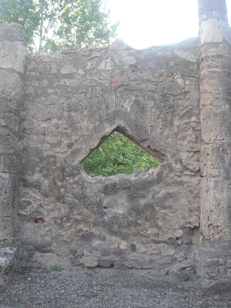 Vicolo dei Soprastanti, Pompeii. May 2011. 
Triangular peephole between Doric columns, set into north wall. Photo courtesy of Ivo van der Graaff
